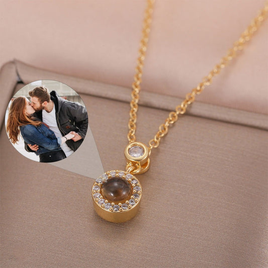 May include: A gold chain necklace with a round pendant. The pendant has a clear stone in the center surrounded by smaller clear stones. The pendant is attached to the chain with a small clear stone.